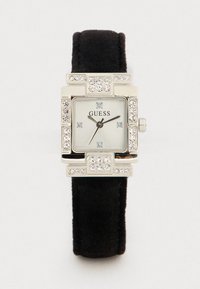 Relógio quadrado prateado com accentos de strass, mostrador branco, bracelete de camurça preta e ponteiros das horas e minutos pretos. Nome da marca "Guess" em destaque.