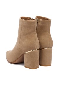 Béžové semišové členkové topánky so zaoblenou špičkou, hrubým podpätkom a zlatým ozdobným detailom na podpätku. Zapínanie na zips vzadu.