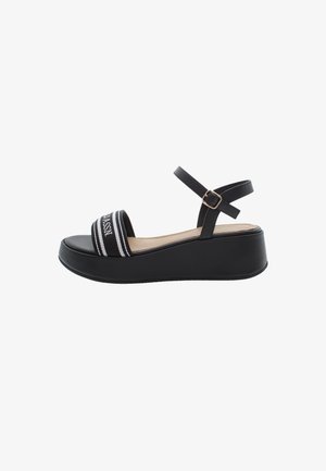 Black platform sandal with a wide strap featuring white and gray stripes, adjustable ankle strap, smooth synthetic material, and textured sole.