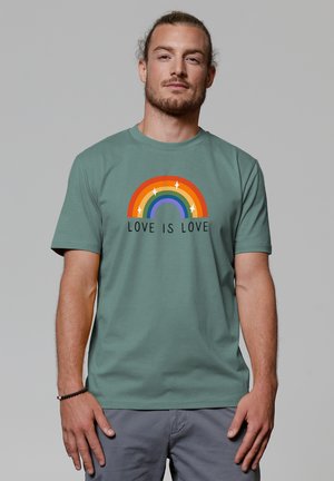 Groene katoenen T-shirt met een multikleurige regenboogafbeelding en de tekst "LIEFDE IS LIEFDE" onder het ontwerp. Soepele textuur, casual pasvorm.