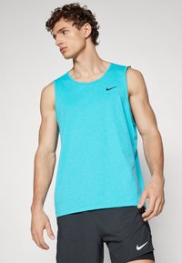 Turquoise sleeveless athletic shirt in a smooth fabric with a crew neck. Features a black Nike logo on the chest and a loose fit.