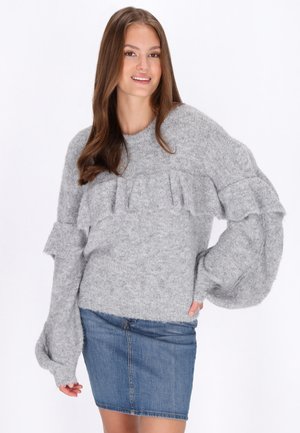 Grå, fluffig tröja med volangdetaljer och långa, fylliga ärmar, parat med en blå denim minikjol.