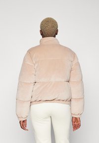 Giacca puff in morbido tessuto rosa chiaro con texture pelosa, colletto alto, polsini elasticizzati e orlo corto.