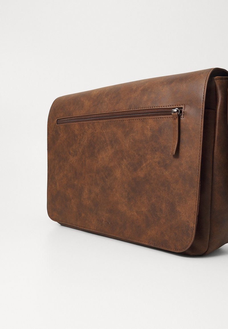 Sac messager en similicuir marron avec une texture lisse, fermeture à rabat, poche avant zippée et forme rectangulaire.