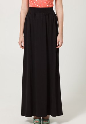 Jupe maxi noire avec une taille élastique, fabriquée en tissu léger, présentant une silhouette fluide qui tombe jusqu'aux chevilles.