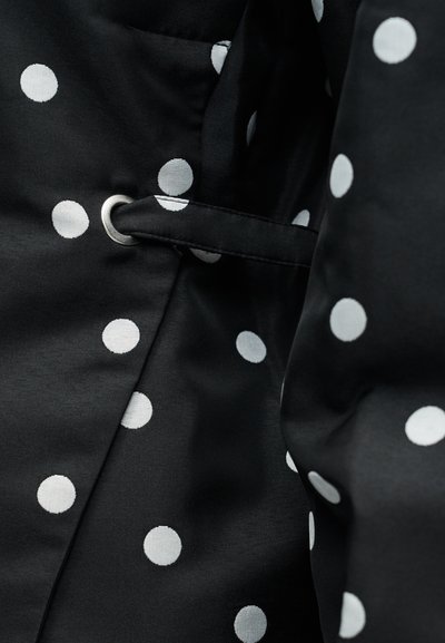 Juoda audinio medžiaga su baltais taškais, sidabrinių detalių ir audinio diržo kilputė. Paviršius yra lygus ir blizgus.