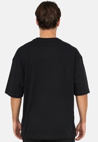 Zwart oversized T-shirt met korte mouwen en een ronde hals, voorzien van een gladde katoenen textuur en nette stikdetails.