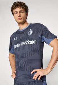 Camisola desportiva de manga curta em azul escuro com padrão texturizado, apresentando um logótipo no peito e decote redondo.