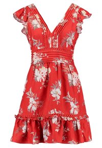 Červené květinové šaty s krátkými volánkovými rukávy, výstřihem do V, plisovanou sukní a rozšířeným volánkovým lemem. Jsou zdobeny bílými a zelenými květinovými vzory.