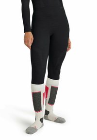 Legging noirs avec un motif texturé ; les chaussettes montantes présentent des sections blanches, grises et rouges avec des textures et des dessins variés.