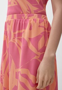 Jurk met een roze en oranje gestreept patroon en abstracte bladdesigns. Gemaakt van lichtgewicht stof met een gerimpelde taille en een gladde textuur.