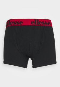 Svarta boxerkalsonger med ett rött elastiskt midjeband som pryds av "ellesse"-logotypen i svart. Tillverkade av mjukt material med en snug passform och slät textur.