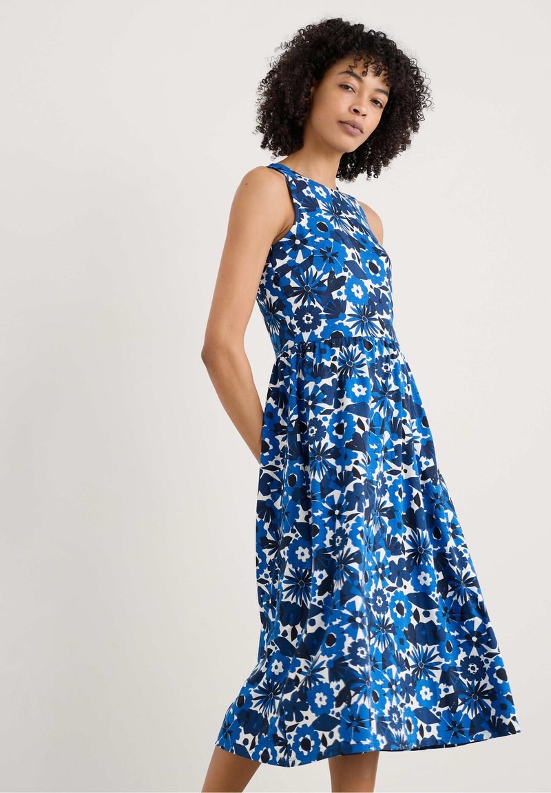 Floral dress featuring a blue and white color palette, sleeveless design, fitted waist, and a flared skirt with pockets.