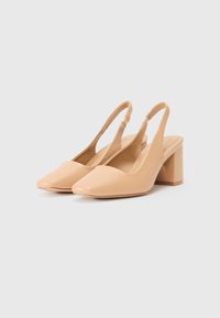 Beige slingback hakken met een vierkante neus en een zware blokhak. Gemaakt van glad materiaal met een glanzende afwerking.