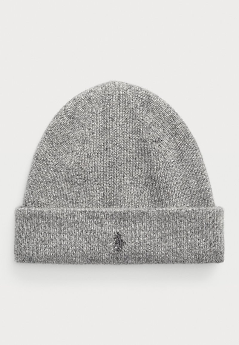 Pelēka adīta cepure, izgatavota no mīksta, ribota materiāla ar paceltu maliņu un nelielu izšūtu logotipa detaļu priekšpusē.