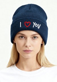 Cappello a maglia blu navy scuro con trama a coste, con ricamo bianco della lettera "I", un cuore rosso e la parola "you" sul davanti.