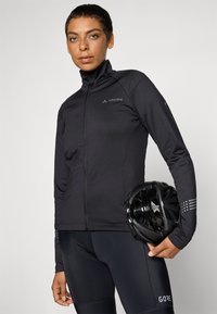 Black cycling jacket with high collar and front zipper; features reflective accents on sleeves and logo at chest; smooth fabric texture.