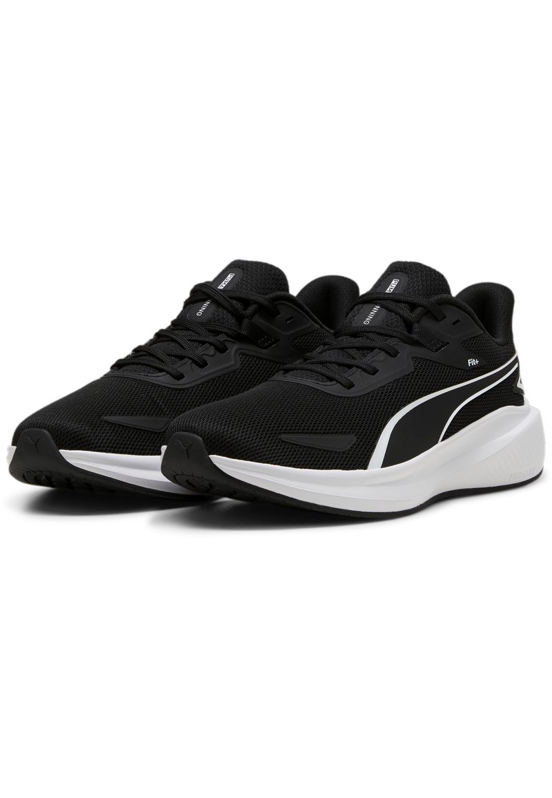 Zapatos deportivos negros con parte superior de malla, acentos blancos y suela de goma plana. Presenta un diseño con cordones y detalles de logo en la lengüeta y el costado.