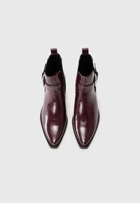 Stivaletti in pelle bordeaux con punta affusolata, texture liscia, dettaglio con fibbia laterale e tacco leggero.