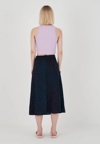 Lila ribbad kort topp i kombination med en svängig svart kjol med ett texturerat mönster av teal- och röda accenter. Enkla sandaler.