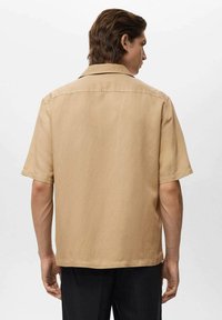Camicia beige a maniche corte con colletto button-down, tessuto liscio e vestibilità rilassata, mostrata da dietro.
