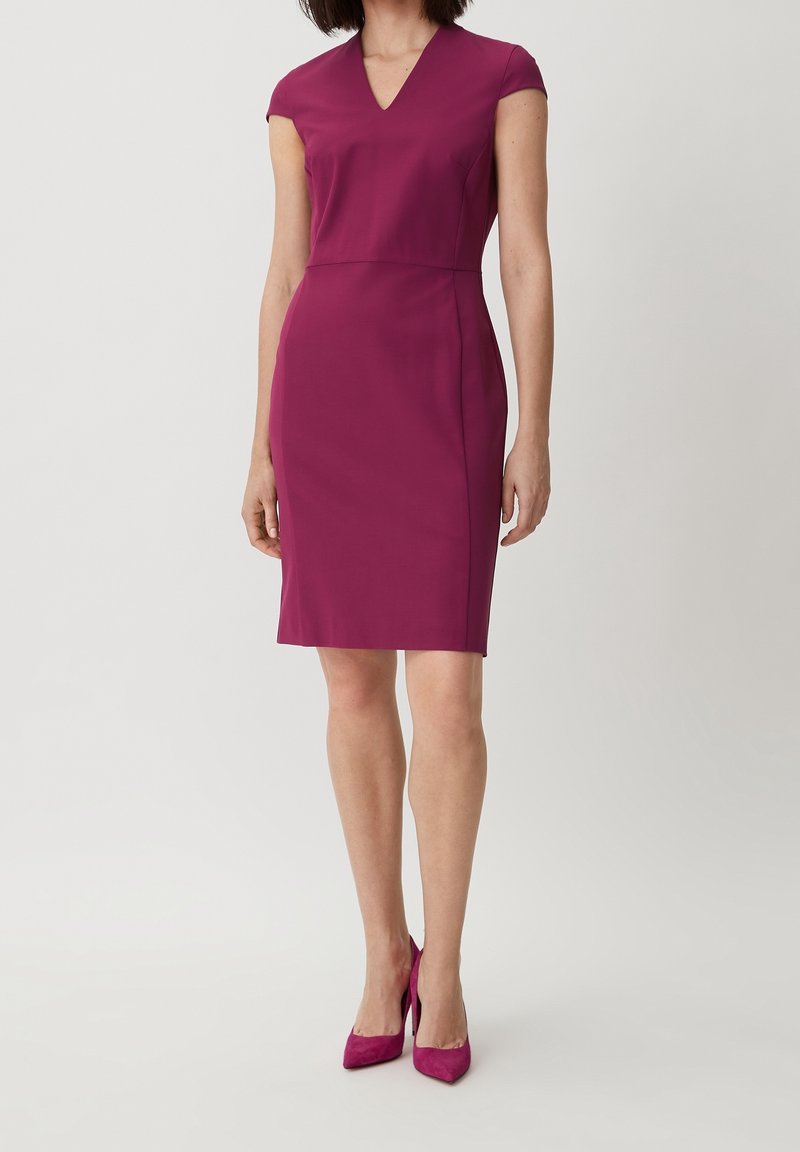 Enganliegendes, ärmelloses Kleid aus leuchtend magentafarbenem Stoff mit V-Ausschnitt und knielangem Saum, kombiniert mit passenden High Heels.