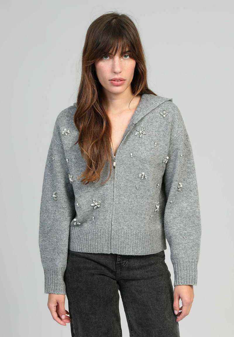 Pull à zip gris en maille douce, orné de détails floraux et doté d'un ourlet et de poignets côtelés. Capuche attachée.