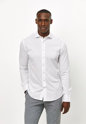 Witte lange mouwen knopsluiting shirt met een klassieke kraag, subtiele textuur en beige knopen, gecombineerd met grijze broeken.