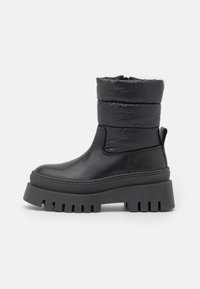 Schwarze Knöchelschuhe mit einem puffigen Nylon-Schaft, dicker schwarzer Gummiplattformsohle und strukturiertem Finish. Mit einer Zuglasche für einfaches Anziehen.