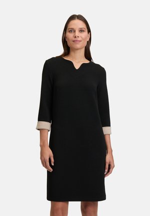 Schwarzes Kleid mit V-Ausschnitt und Dreiviertelärmeln, ausgestattet mit hellbeigen Bündchen, strukturiertem Stoff und zwei vorderen Taschen.