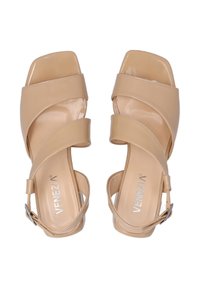 Beige High Heels Sandalen mit überkreuzten Riemen und quadratischer Zehenform, ausgestattet mit einem glatten, glänzenden Finish und einem Fesselverschluss.