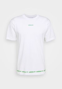 Vit bomull t-shirt med grön "adidas" logo på bröstet och upprepad grön branding l ängs fållen. Klassisk rund hals och korta ärmar.