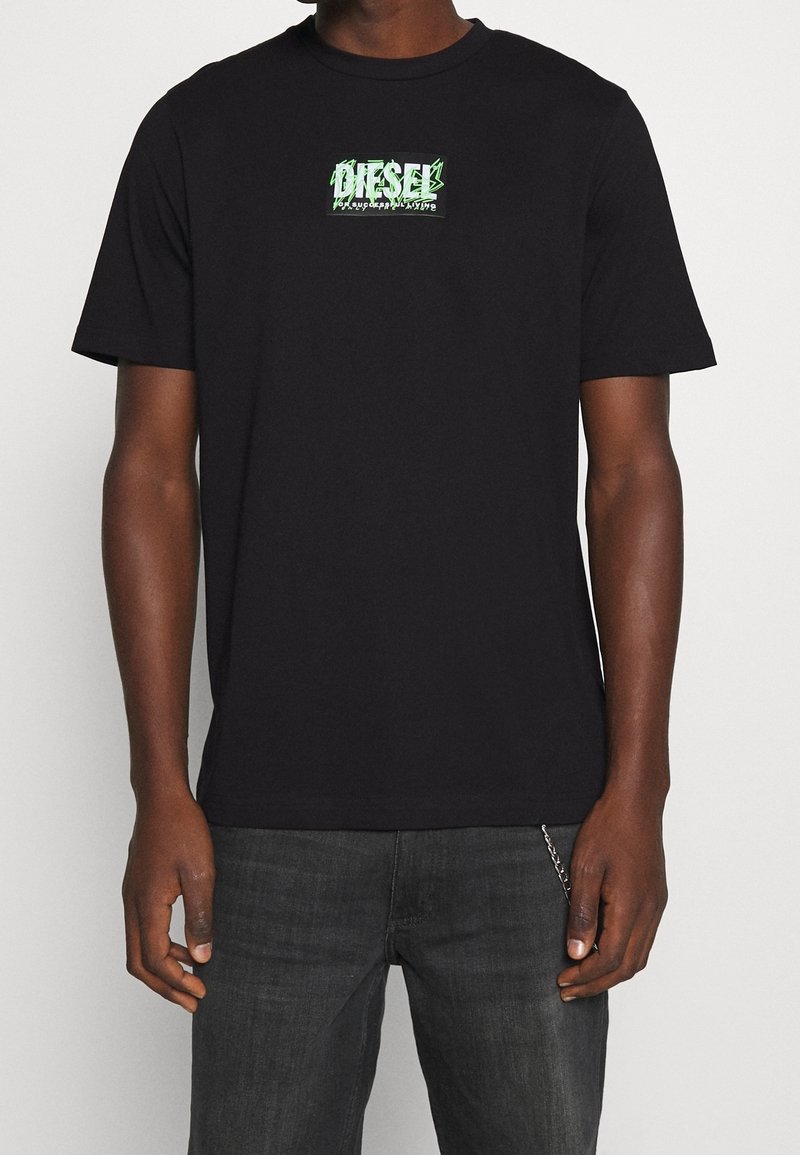 Černé bavlněné tričko s zeleným grafickým logem na hrudi. Design s kulatým výstřihem; krátké rukávy s klasickým střihem.