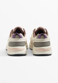 Lehké krémově zbarvené tenisky s texturovaným povrchem. Mají hnědé detaily, fialové poutka na patě a gumovou podrážku pro lepší přilnavost.