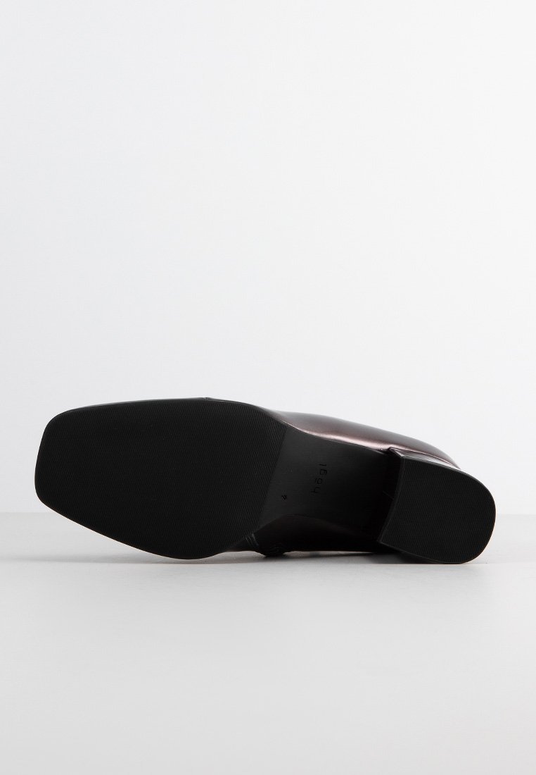 Suola di scarpa nera con superficie liscia e strutturata. Presenta una punta arrotondata e un tacco leggero, realizzata in un materiale scuro e lucido.