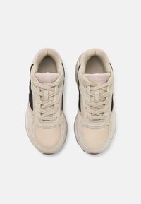 Sapatos de desporto bege com pormenores em malha preta, acabamentos em camurça e uma sola em borracha texturizada. Apresentam atacadores e um interior suave.