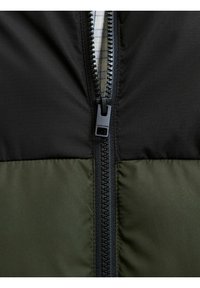 Giubbotto imbottito nero e verde oliva. Presenta una zip robusta e una superficie liscia. La fodera interna presenta un motivo a quadri.