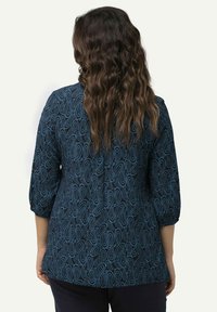 Blusa blu navy con maniche tre quarti, caratterizzata da un motivo paisley vorticoso in blu più chiaro, realizzata in un tessuto testurizzato.
