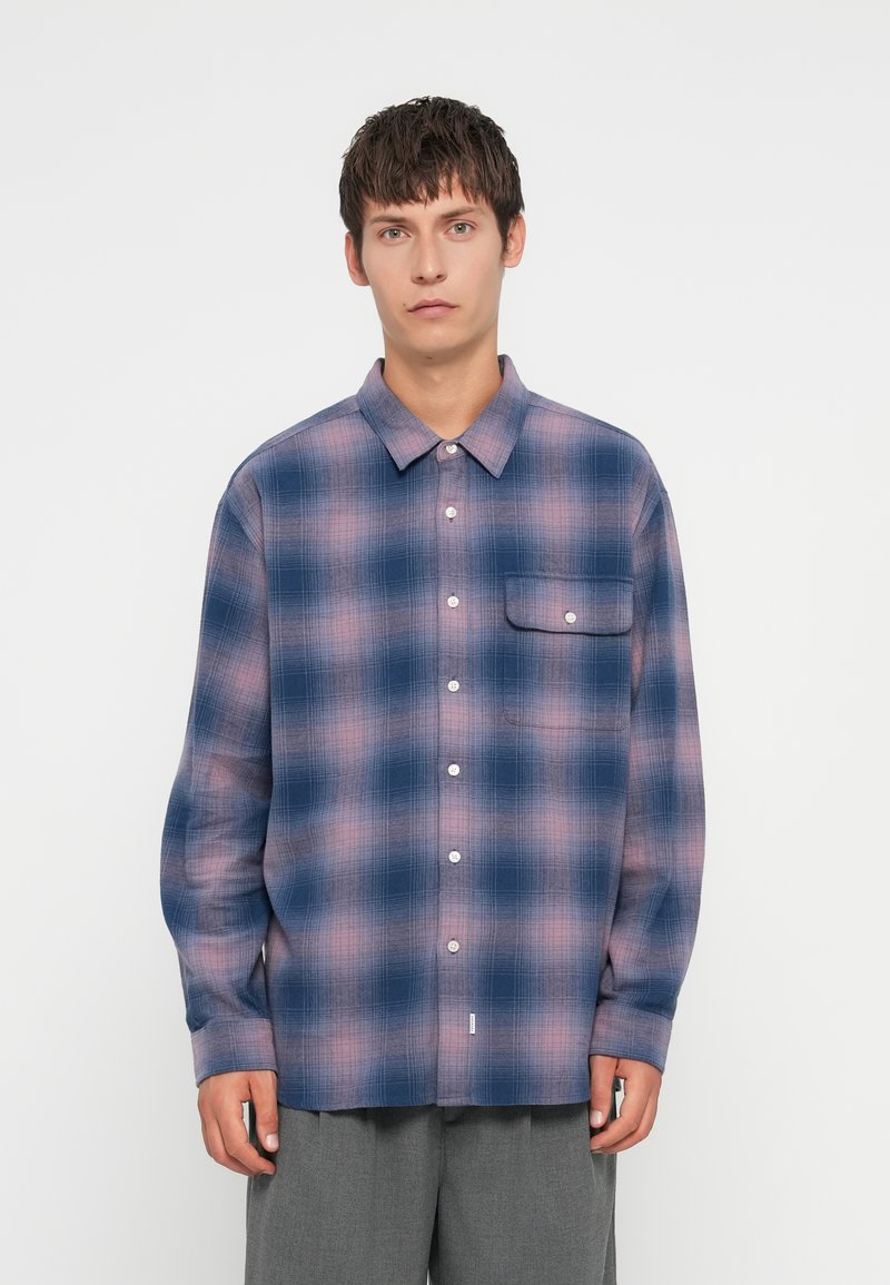 Button-up shirt with a blue and pink plaid pattern, long sleeves, and a front pocket, made of a soft fabric with a smooth texture.