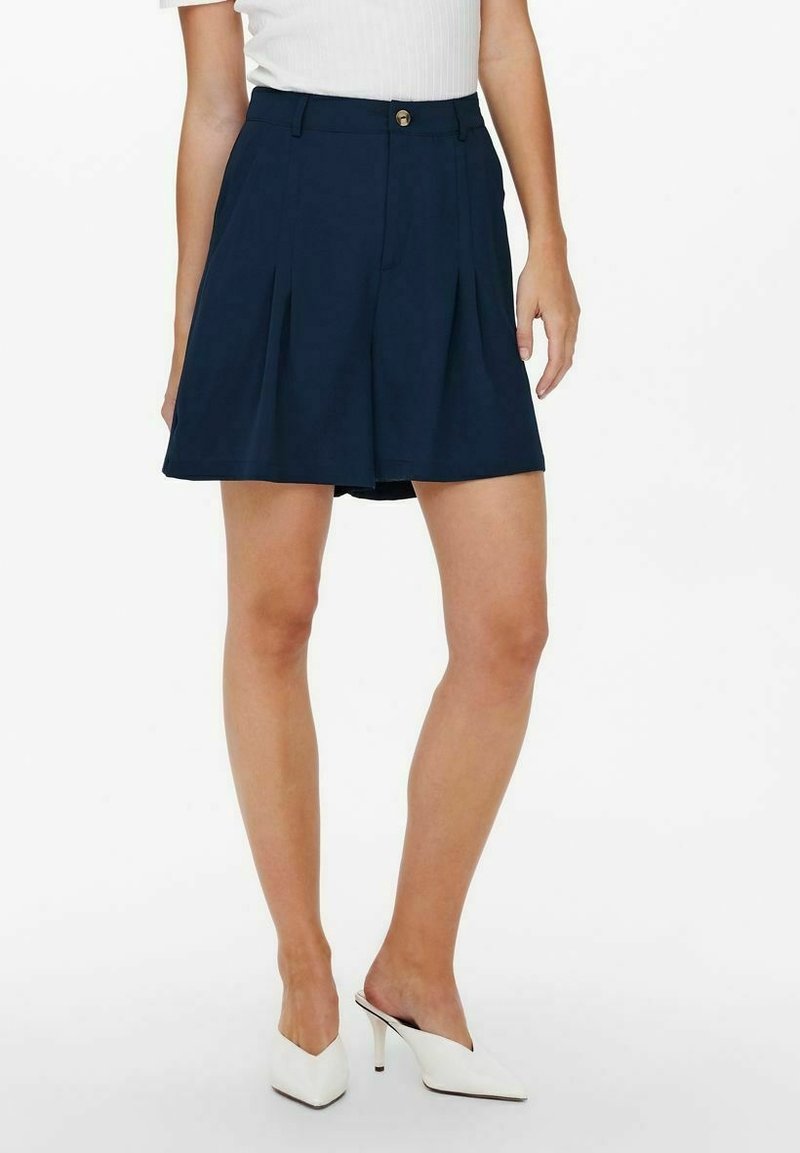 Granatowe plisowane spodenki o gładkiej fakturze, z zapięciem na przód na guziki i ukrytymi bocznymi kieszeniami. Dopasowany design sięgający do kolan.