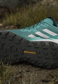 Scarpa da ginnastica turchese con strisce bianche, tomaia testurizzata e suola in gomma nera con un motivo di profilo distintivo e marchio Continental.
