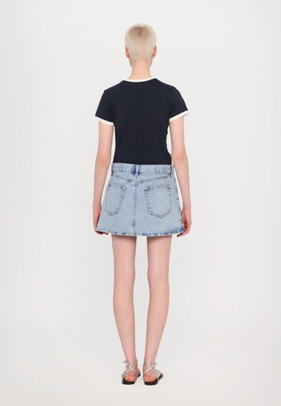 Navy short-sleeve shirt with white trim paired with a light blue denim skirt. The skirt has a flared shape and back pockets. Black sandals.