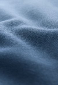 Weicher, hellblauer Strickstoff mit sanften Falten und einem aus nächster Nähe sichtbaren strukturierten Webmuster.