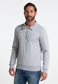 Harmaa vetoketjullinen collegepusero, jossa on pitkät hihat ja ribbaus hihoissa. Mukana vaakasuora sauma ja ankkurilogo.