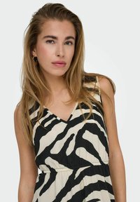 Vestido sin mangas con escote en V que presenta un estampado de cebra en negro y crema, con una cintura fruncida y una tela suave y texturizada.