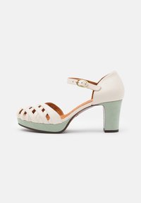 Chaussure à talon haut en cuir blanc avec devant tissé, plateforme texturée couleur menthe, et bride de cheville ajustable avec boucle en or.