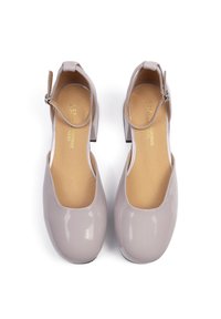 Escarpins en cuir verni gris clair avec un bout rond, une bride à la cheville et un petit talon carré. Texture lisse et design simple.