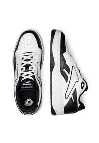 Biele a čierne tenisky s hladkým koženým zvrškom, perforovanou špičkou, šnurovací konštrukciou, polstrovaným golierom a gumovou podrážkou s detailmi zachytávajúcimi trakciu.