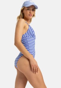 Maillot de bain une pièce à rayures bleues et blanches avec un design ajusté, mettant en avant un dos croisé et des accents de finition texturée.