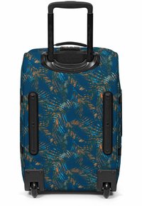Maleta de ruedas con una base azul, que presenta un colorido patrón de hojas de palmera en naranja, verde y marrón. Se pueden ver el asa y las ruedas en negro.
